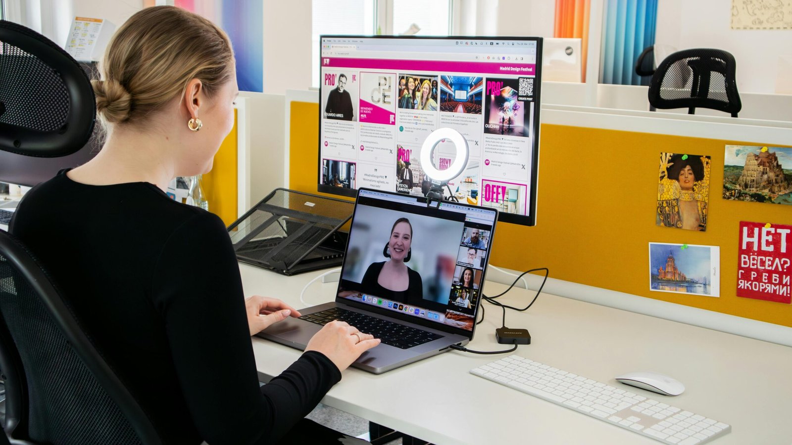 A virtual assistant conducts a professional video call while working at her desk in a bright office setting.